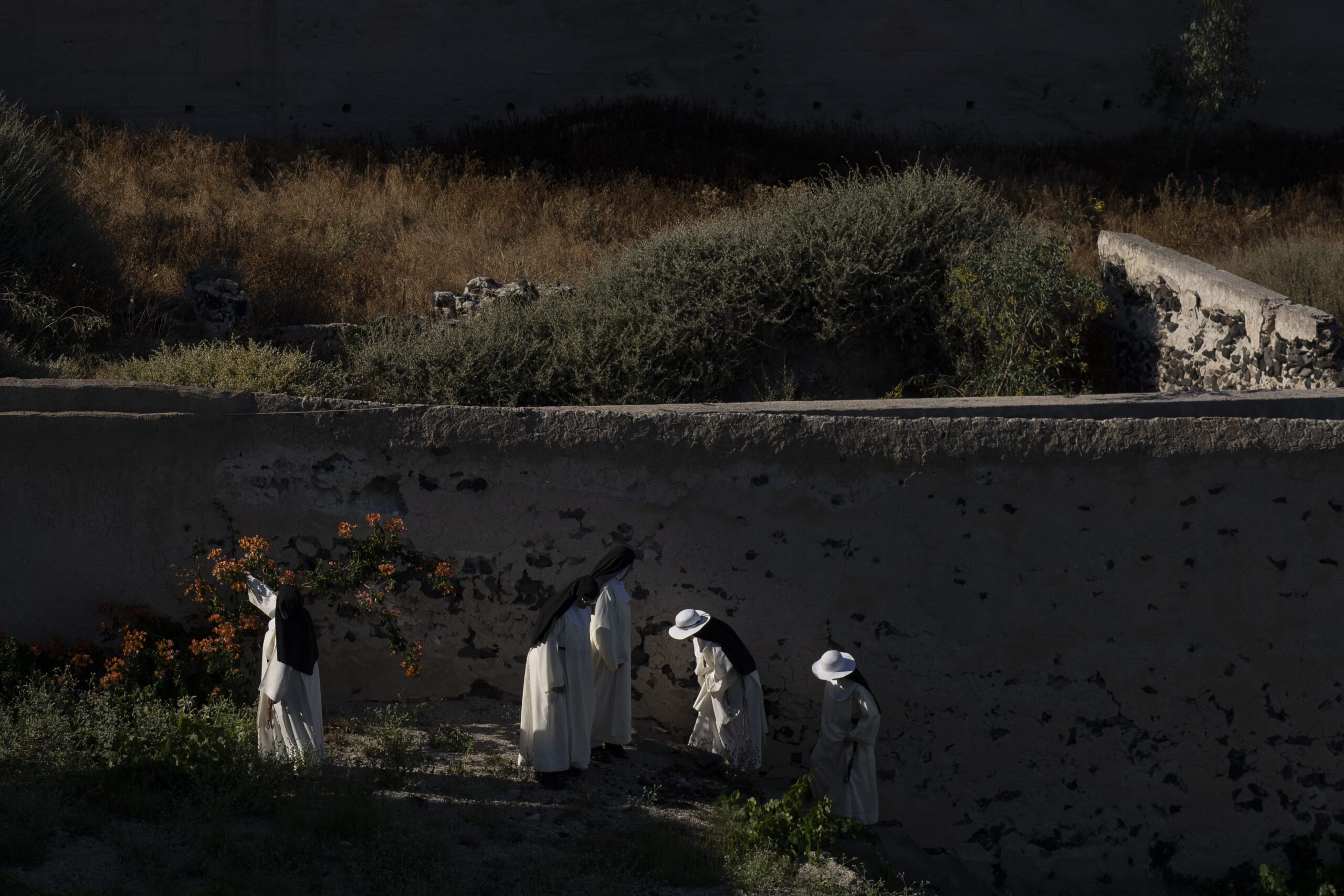 Cloistered nuns walk in the garden of the Catholic Monastery of St. Catherine on the Greek island of Santorini on Wednesday, June 15, 2022. When not praying in church or practicing sacred music and hymns, the nuns tend to the garden, where they grow fruits and vegetables. (AP Photo/Petros Giannakouris)