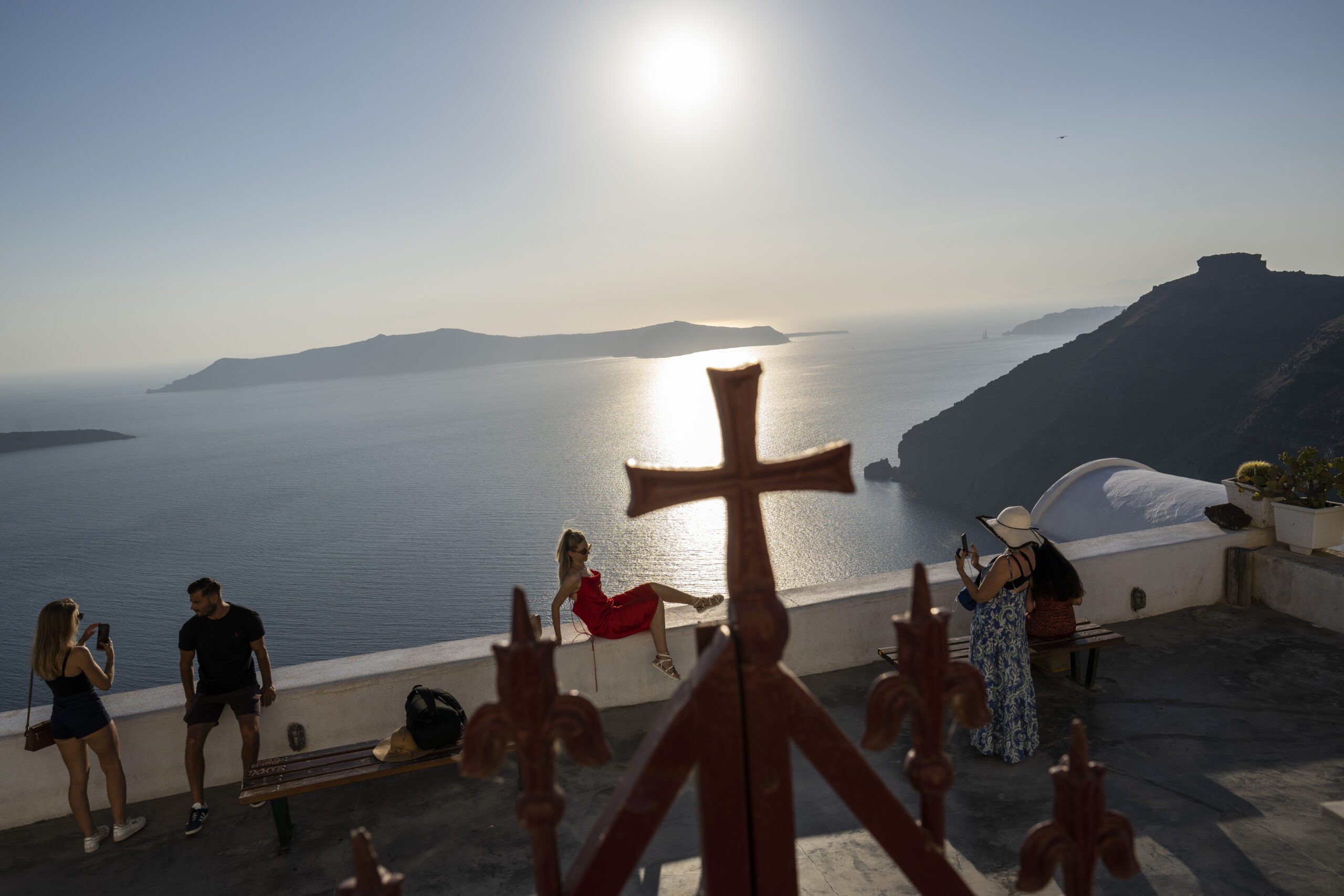 A woman poses for a photograph outside the wrought-iron enclosure of the Dormition of the Virgin Mary Catholic Church on the Greek island of Santorini on Wednesday, June 15, 2022. The Monastery of St. Catherine is home to more than a dozen nuns who devote themselves to tireless prayer. (AP Photo/Petros Giannakouris)