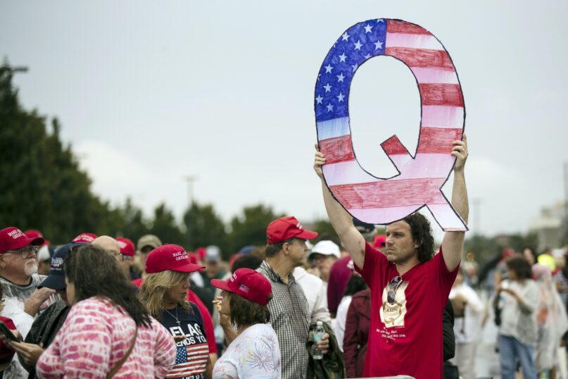 A protester holds a Q sign as he waits to enter a campaign rally with then-President Donald Trump in Wilkes-Barre, Pa., in August 2018. (AP Photo/Matt Rourke)