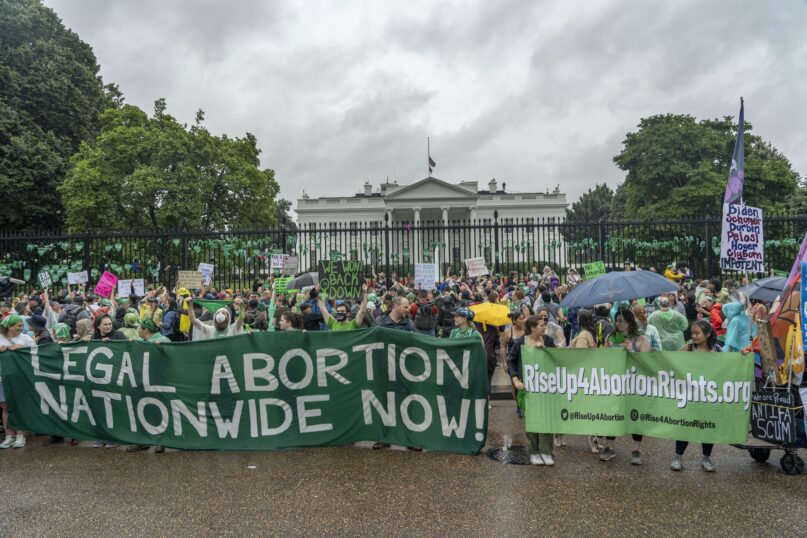 Abortion-rights protesters shout slogans after tying green flags to the fence of the White House in Washington, D.C. on July 9, 2022. (AP Photo/Gemunu Amarasinghe)