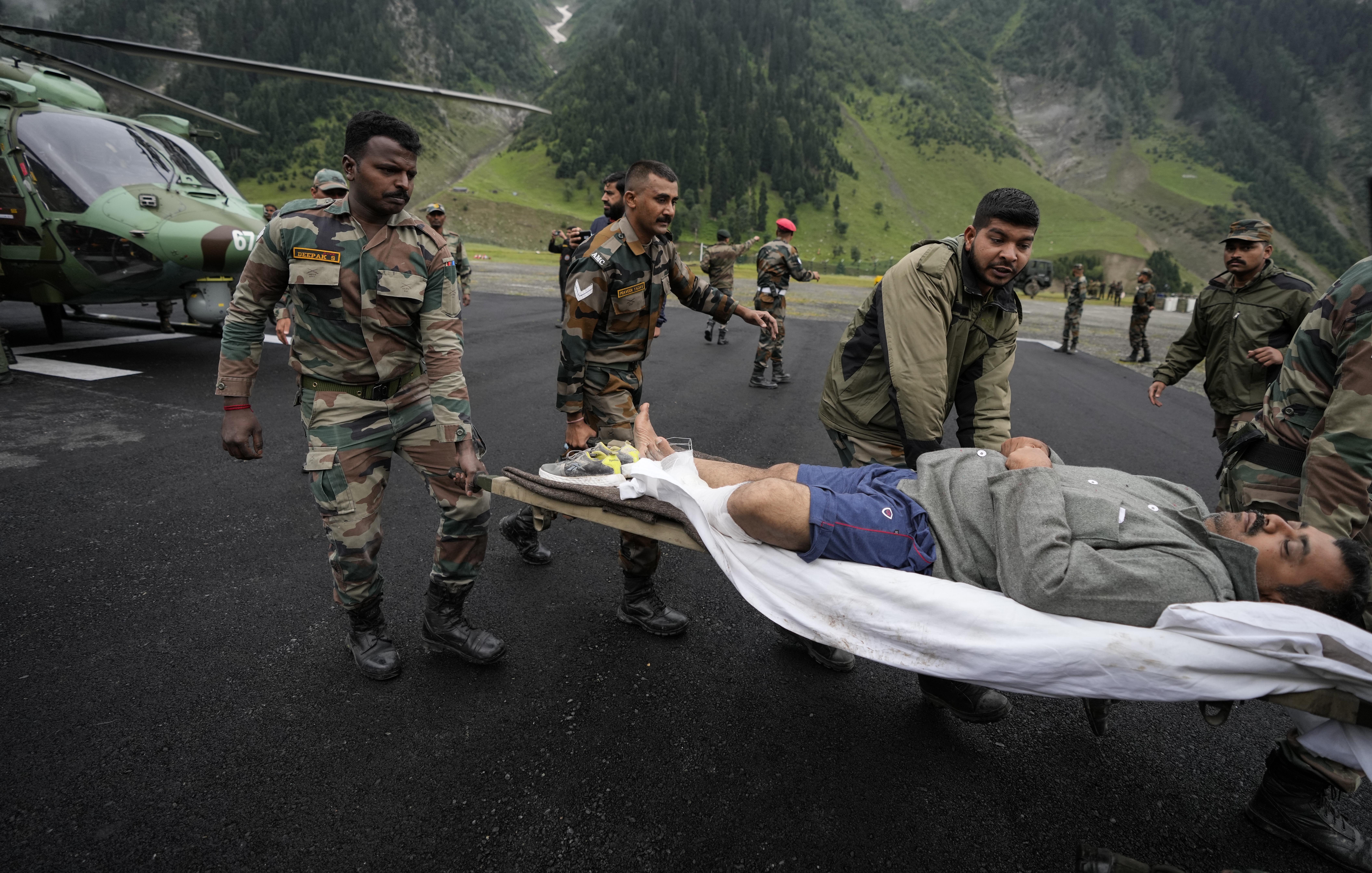 Indian army soldiers carry an injured of a cloudburst for treatment, at Baltal, 105 kilometers (65miles) northeast of Srinagar, Indian controlled Kashmir, Saturday, July 9, 2022. At least eight pilgrims have been killed after a cloudburst triggered a flash flooding during an annual Hindu pilgrimage to an icy Himalayan cave in Indian-controlled Kashmir. Officials say the cloudburst near the hollowed mountain cave revered by Hindus on Friday sent a wall of water down a mountain gorge and swept about two dozen encampments and two makeshift kitchens. (AP Photo/Mukhtar Khan)