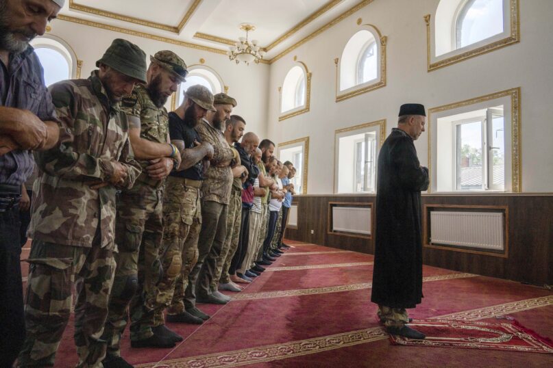 Former Mufti Sheikh Said Ismahilov, leads Muslim soldiers during prayers on the first day of Eid al-Adha, in Medina Mosque, Konstantinovka, eastern Ukraine, Saturday, July 9, 2022. Muslims around the world celebrate Eid al-Adha by sacrificing animals to commemorate the prophet Ibrahim's faith in being willing to sacrifice his son. (AP Photo/Nariman El-Mofty)