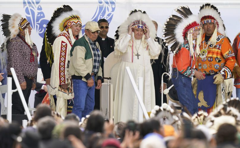 Pope Francis dons a headdress during a visit with Indigenous peoples at Maskwacis, the former Ermineskin Residential School, July 25, 2022, in Maskwacis, Alberta. Francis traveled to Canada to apologize to Indigenous peoples for the abuses committed by Catholic missionaries in the country’s notorious residential schools. (AP Photo/Eric Gay)