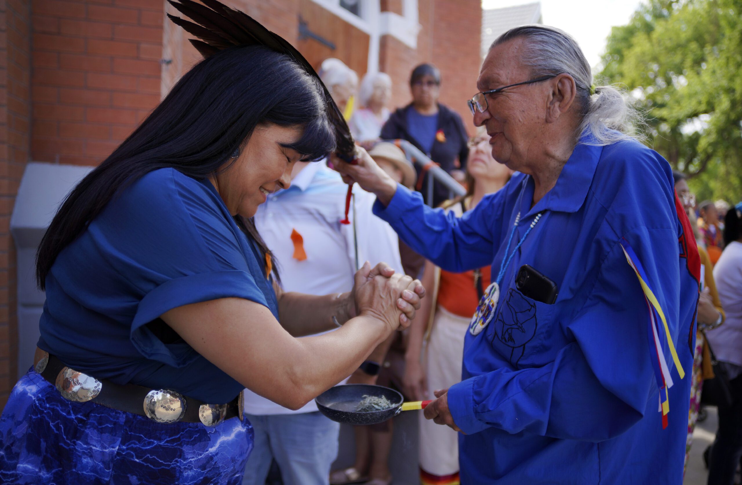 Marlene Poitras participates in a smudging, a ceremonial burning of scented plants for purification and blessing, with church elder Fernie Marty outside of Sacred Heart Church of the First Peoples on Sunday, July 17, 2022, in Edmonton, Alberta. Marty is a survivor of a day school for Indigenous children, which had culturally repressive policies similar to that of residential schools. He has continued practicing his Catholic faith in conjunction with Indigenous ceremonies. (AP Photo/Jessie Wardarski)