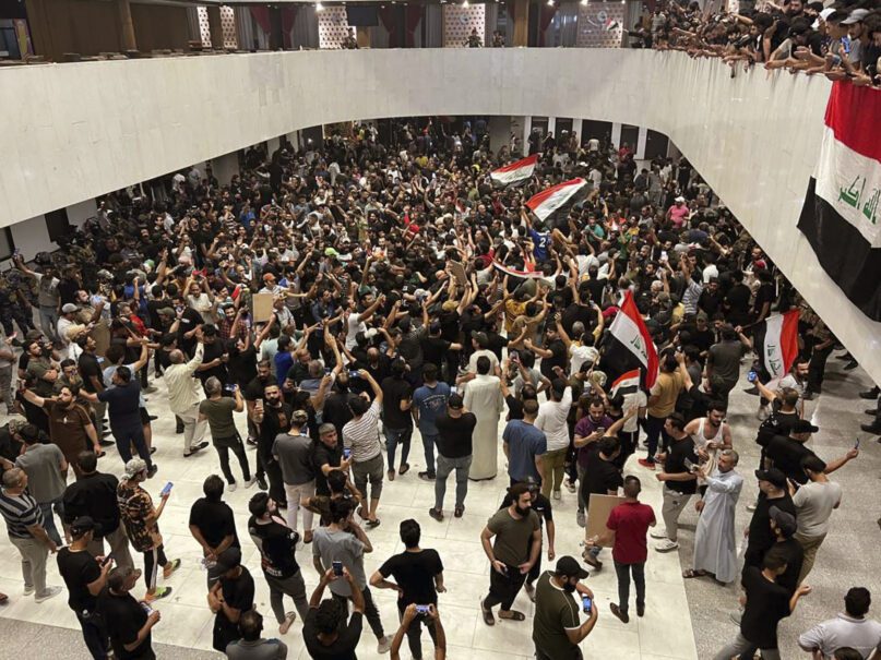 Hundreds of Iraqi protesters breached Baghdad's parliament in Baghdad, Iraq, Wednesday, July. 27, 2022.  The majority of the protesters were followers of influential Shiite cleric Muqtada al-Sadr. The demonstrators, all of them men, were seen walking on tables of the parliament floor, sitting in the chairs of lawmakers and waving Iraqi flags.  (AP Photo/Ali Abdul Hassan)