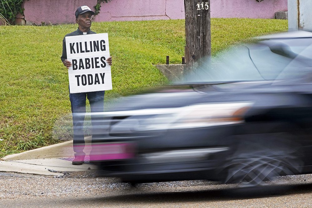 Anti-abortion activist E.C. Smith, stands outside the Jackson Women's Health Organization clinic with his message sign as traffic rushes by in Jackson, Miss., Monday, June 27, 2022. Aware that the clinic, only had limited staffing and were not performing any medical procedures, he said he had made a pact with God to protest every day outside the clinic until all abortions ceased. On Friday, June 24, the U.S. Supreme Court overturned Roe v. Wade, ending constitutional protections for abortion. (AP Photo/Rogelio V. Solis)