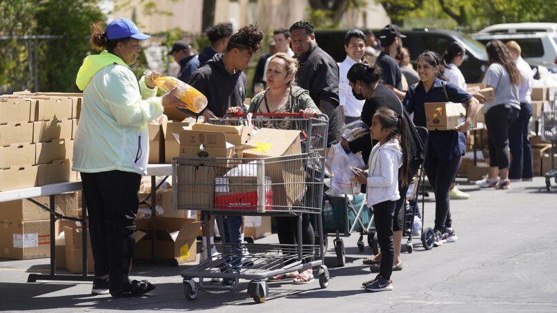 A Utah Food Bank volunteer, left, loads groceries for recipients at a food bank distribution May 13, 2022, in Salt Lake City. (AP Photo/Rick Bowmer)