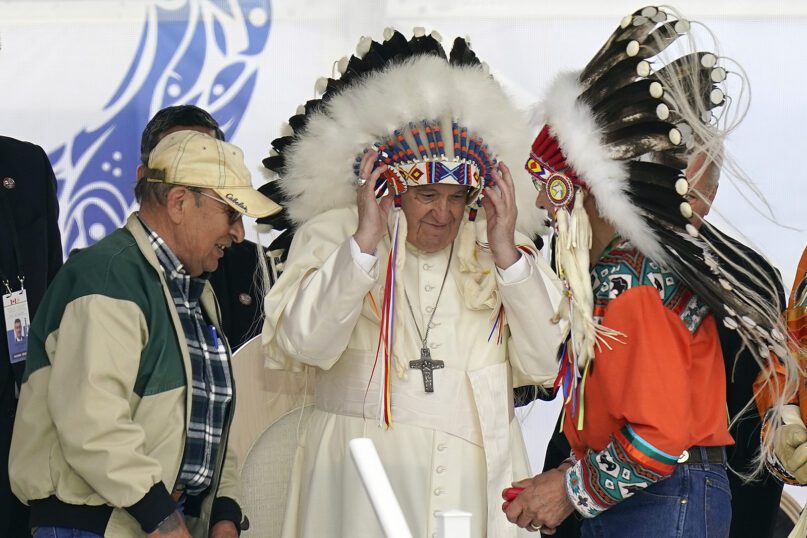 Pope Francis puts on an Indigenous headdress during a meeting with Indigenous communities, including First Nations, Métis and Inuit, at Our Lady of Seven Sorrows Catholic Church in Maskwacis, near Edmonton, Canada, Monday, July 25, 2022. Pope Francis begins a 