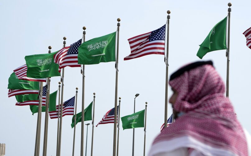 A man stands under American and Saudi Arabian flags ahead of a visit by U.S. President Joe Biden, at a square in Jeddah, Saudi Arabia, July 14, 2022. (AP Photo/Amr Nabil)