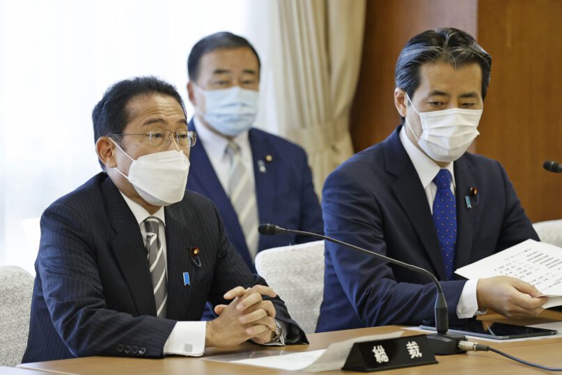 Japanese Prime Minister Fumio Kishida, left, greets at the beginning of a meeting with his party members at the party's headquarters in Tokyo, Wednesday, Aug. 10, 2022. Kishida is set to reshuffle his Cabinet on Wednesday in a move seen as trying to distance his administration from controversial ties to the Unification Church following former leader Shinzo Abe's assassination. (Hironori Asakawa/Kyodo News via AP)