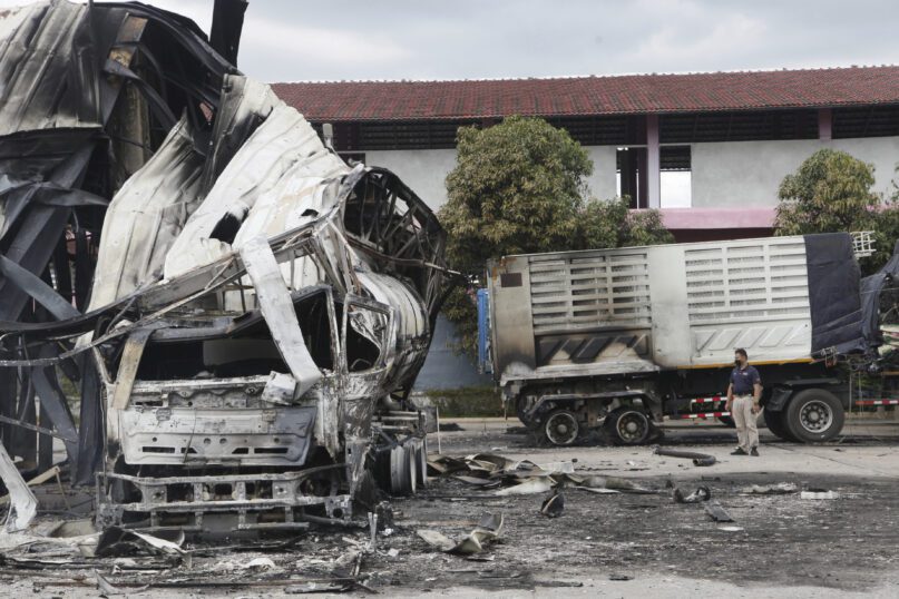 A Thai officer stands beside the burnt down oil tanker at a gas station in Pattani province, southern Thailand, Wednesday, Aug. 17, 2022. A wave of arson and bombing attacks overnight hit Thailand’s southernmost provinces, which for almost two decades have been the scene of an active Muslim separatist insurgency, officials said Wednesday. (AP Photo/Sumeth Panpetch)