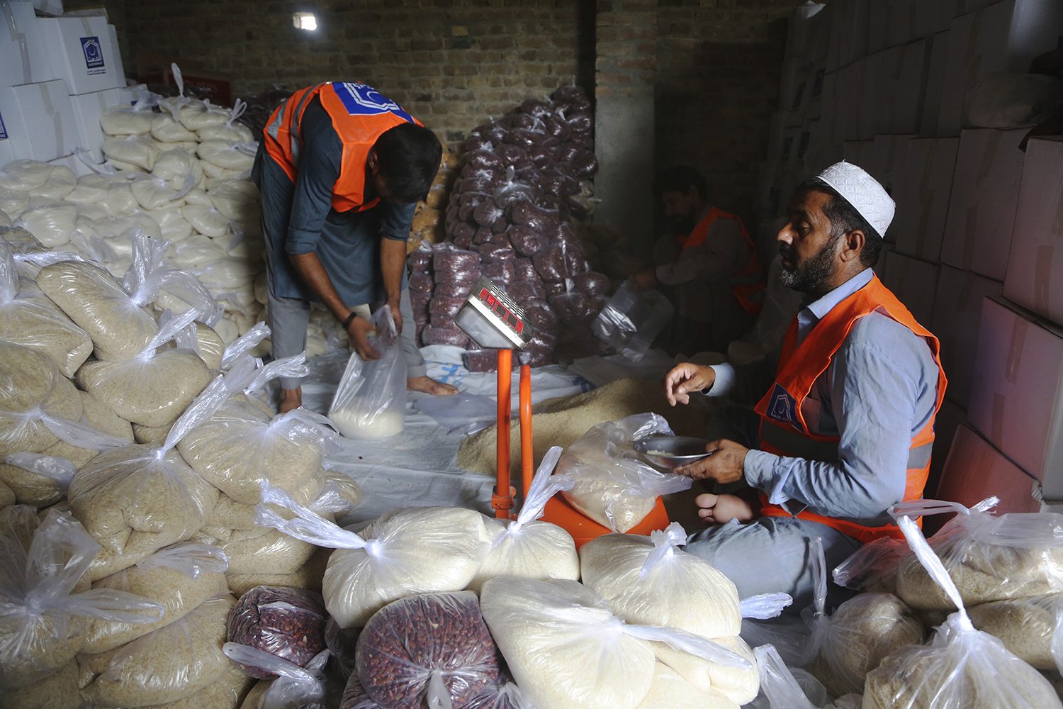 Volunteers form an Islamic charity group prepares food packets to be send into flood-hit areas, in Peshawar, Pakistan, Friday, Aug. 26, 2022. Pakistan's government in an overnight appeal sought relief assistance from the international community for flood-affected people in this impoverished Islamic nation, as the exceptionally heavier monsoon rain in recent decades continued lashing various parts of the country, killing more people and raising the overall death toll from mid-June to 937. (AP Photo/Muhammad Sajjad)
