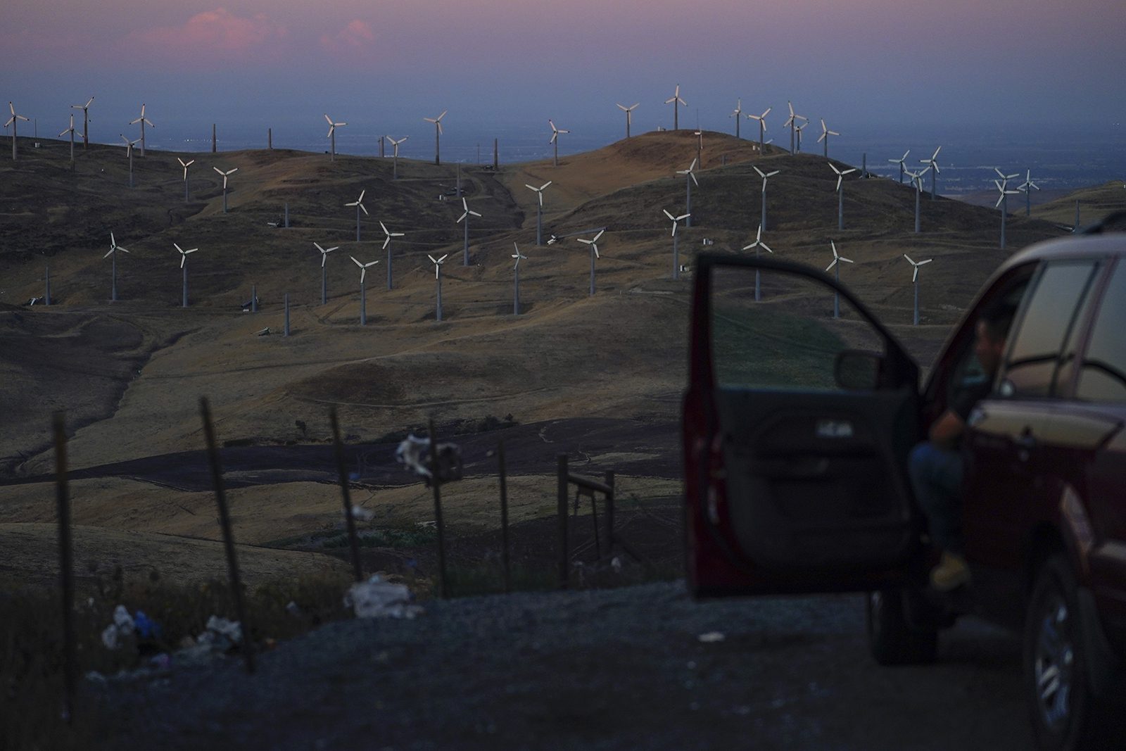 A man looks out at wind turbines in Livermore, Calif., Wednesday, Aug. 10, 2022. Congress is poised to pass a transformative climate change bill on Friday, Aug. 12. The crux of the long-delayed bill is to use incentives to accelerate the expansion of clean energy such as wind and solar power, speeding the transition away from the oil, coal and gas that largely cause climate change. (AP Photo/Godofredo A. Vásquez)