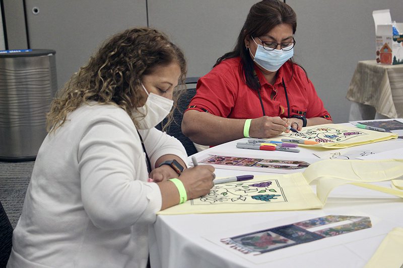Attendees color bags designed by an Ojibwe artist in the American Indian/Alaska Native Community Learning Space near the hall in the Greater Columbus Convention Center during the ELCA Churchwide Assembly, Aug. 10, 2022, in Columbus, Ohio. RNS photo by Emily McFarlan Miller
