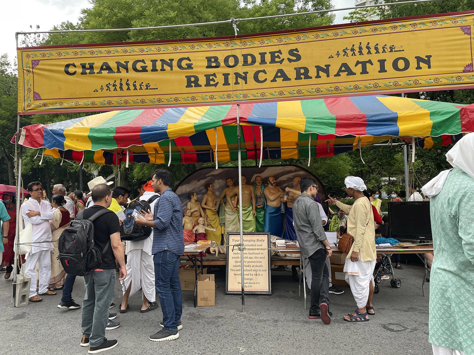 People surround a booth about reincarnation during the Hare Krishna Festival at Washington Square Park on June 11, 2022, in Manhattan, New York. RNS photo by Richa Karmarkar