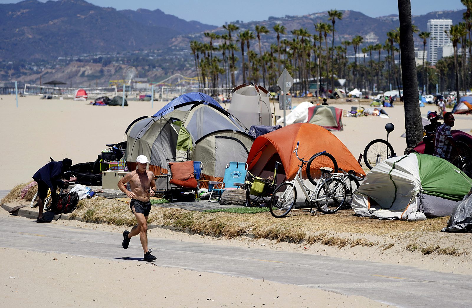 A jogger runs past a homeless encampment in the Venice Beach section of Los Angeles on June 8, 2021. (AP Photo/Marcio Jose Sanchez, File)