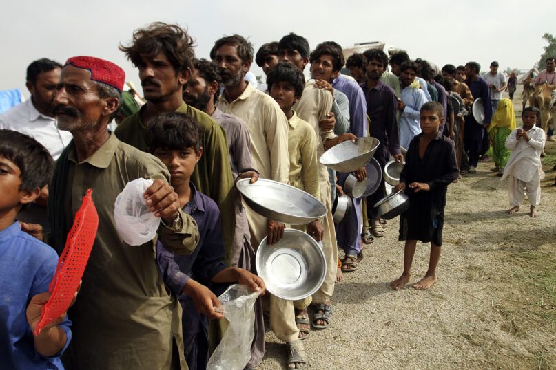 People displaced by flooding wait in a long line to receive food distributed by Pakistani army troops in a flood-hit area in the Rajanpur district of Punjab, Pakistan, Aug. 27, 2022. Officials say flash floods triggered by heavy monsoon rains across much of Pakistan have killed nearly 1,000 people and displaced hundreds of thousands more since mid-June. (AP Photo/Asim Tanveer)
