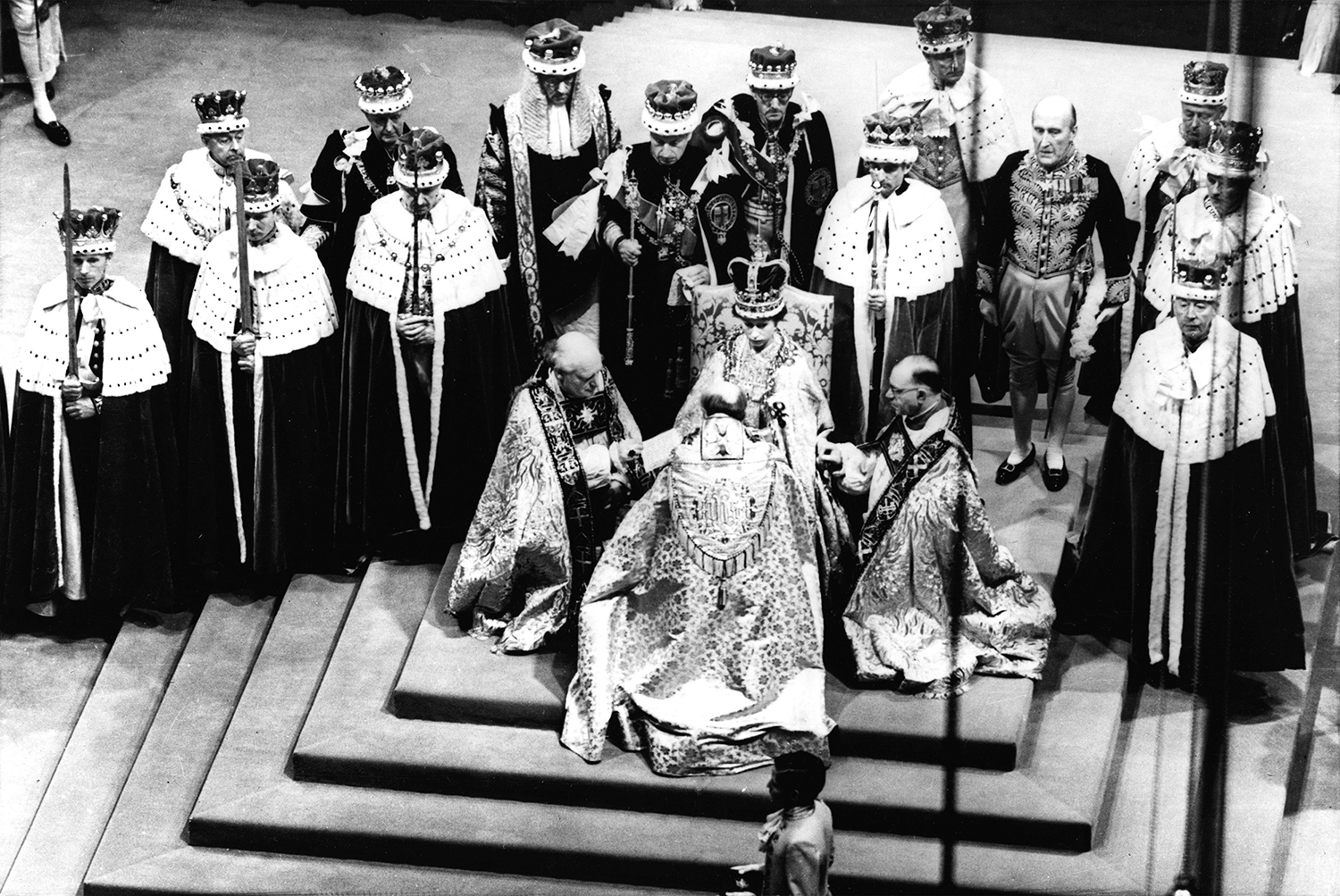 FILE - In this June 2, 1953 file photo, Britain's Queen Elizabeth II, seated on the throne, receives the fealty of the Archbishop of Canterbury, back to camera at center, the Bishop of Durham, left, and the Bishop of Bath and Wells, during her coronation in Westminster Abbey, London. (AP Photo, File)