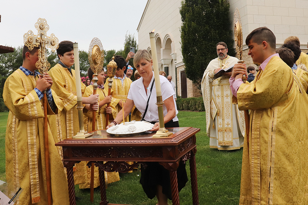 Dr. Lisa Liberatore, center, carries a Koliva, which is prepared for memorial services in Orthodox churches and consists of boiled wheat, powdered sugar and almonds, during a service at Dormition of the Virgin Mary Greek Orthodox Church of the Hamptons in Southampton, New York, on Sept. 11, 2022. RNS photo by Adelle M. Banks