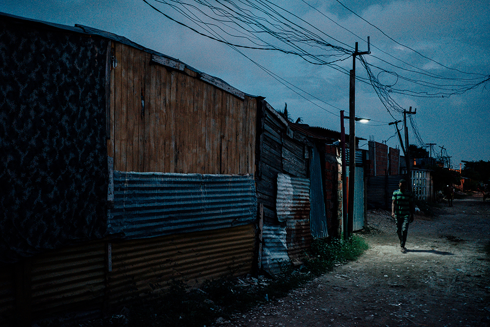 A man passes below a street light at dusk in the Isla de León neighborhood of Cartagena, Colombia, in May 2022. Photo by Noel Rojo