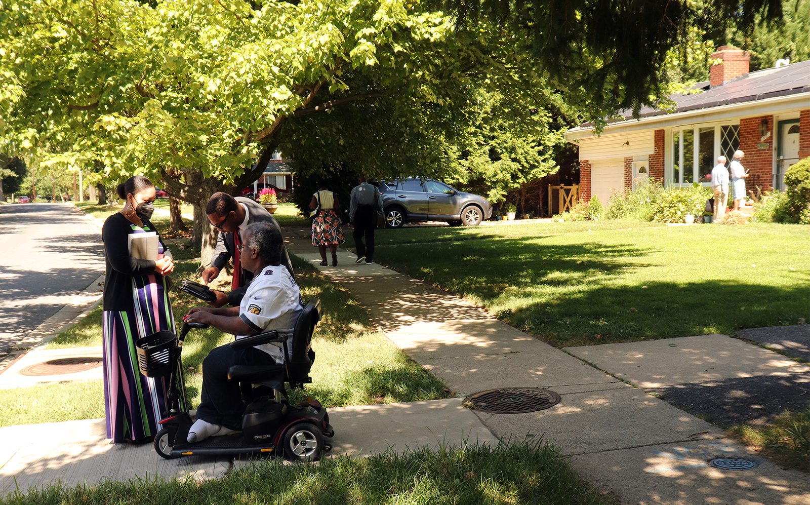 Tameka and Limmel Richardson, of Silver Spring, Maryland, speak with resident Charles Ogwo, seated, as other Jehovah’s Witnesses head to nearby houses in the community to knock on doors as they returned to the traditional practice on Thursday, Sept. 1, 2022. RNS photo by Adelle M. Banks