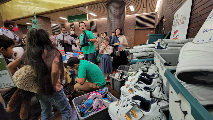 Masbia Relief Team members, in green, distribute shoes and other aid to asylum-seekers arriving at the Port Authority Bus Terminal in Manhattan, New York, on Aug. 19, 2022. Photo courtesy of Masbia