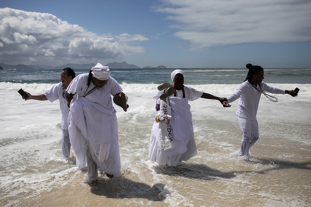 Faithful of the Afro-Brazilian religion Candomble walk on the shore before a Defense of Religious Freedom march at Copacabana Beach in Rio de Janeiro, Brazil, Sunday, 18 Sept. 2022. The march seeks to draw the attention of society and public authorities to the growth of cases of religious intolerance in the country. (AP Photo/Bruna Prado)