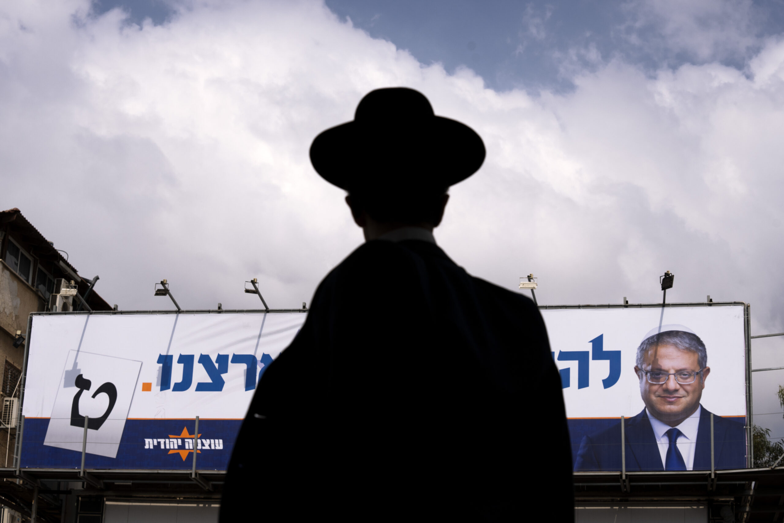 An ultra-Orthodox Jewish man walks by an election campaign billboard showing Itamar Ben-Gvir, Israeli far-right lawmaker and the head of "Jewish Power" party, in Bnei Brak, Israel Monday, Oct. 24, 2022. Israel is holding its fourth election in less than two years. Israel's most extremist politician, known for his inflammatory anti-Arab speeches and stunts, is attracting new supporters from a previously untapped demographic young ultra-Orthodox Jews, one of the fastest-growing segments of the country's population. (AP Photo/Oded Balilty)