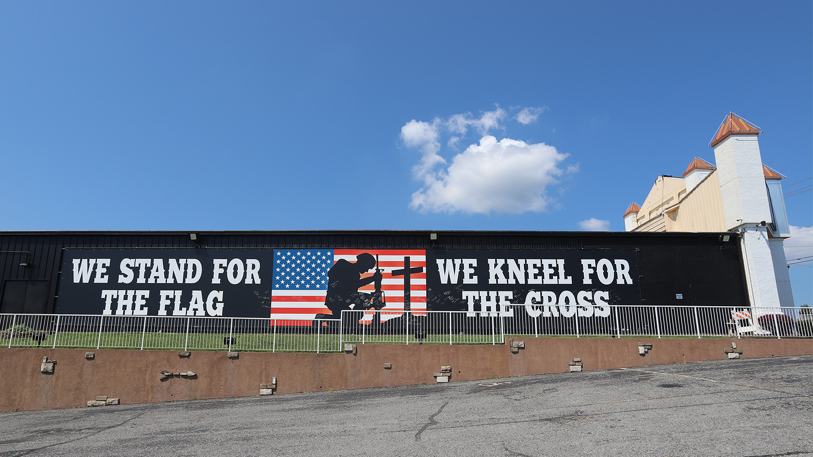 A large sign reading "We stand for the flag. We kneel for the cross." covers the side of the Pierce Arrow Theater in Branson, Mo. RNS photo by Kit Doyle
