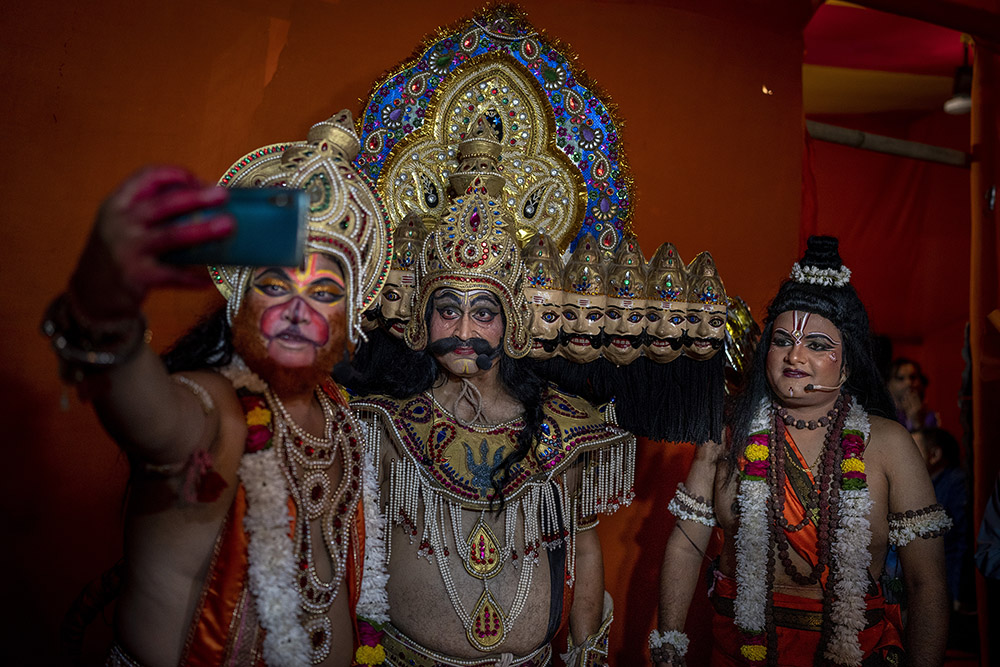 An artist dressed as Hindu monkey god Hanuman, left, takes a selfie with artists dressed as demon king Ravana, center, and Hindu god Ram, right, before a final Ramleela performance as part of Dussehra festival celebrations in New Delhi, India, Wednesday, Oct. 5, 2022. Ramleela is a dramatic folk re-enactment of the life of Hindu lord Rama. After the enactment of the legendary war between Good and Evil, the Ramleela celebrations climax in the Dussehra night festivities where the giant effigies of demon King Ravana, his brother Kumbakaran and son Meghnad are burned, typically with fireworks. (AP Photo/Altaf Qadri)