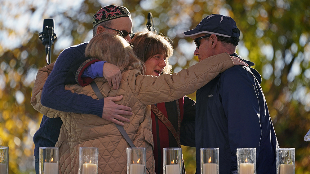 People hug after lighting a candle in memory of Melvin Wax, Thursday, Oct. 27.  At a memorial service in Pittsburgh on Sunday, one of 11 worshipers killed four years ago when a gunman opened fire at Tree of Life Synagogue in the Squirrel Hill neighborhood.  2022. (AP Photo/Gene J. Puskar)