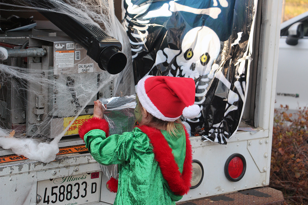 A costumed child holds up a bag to receive candy from Carl Masters in his pirate-themed Mr. Gutter truck during the Baker Memorial United Methodist Church trunk or treat, Sunday, Oct. 23, 2022, in St. Charles, Illinois. RNS photo by Emily McFarlan Miller