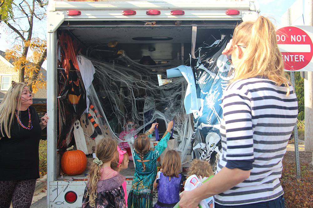 Costumed children hold up bags to receive candy from Carl Masters in his Mr. Gutter truck during the Baker Memorial United Methodist Church trunk or treat, Sunday, Oct. 23, 2022, in St. Charles, Illinois. RNS photo by Emily McFarlan Miller