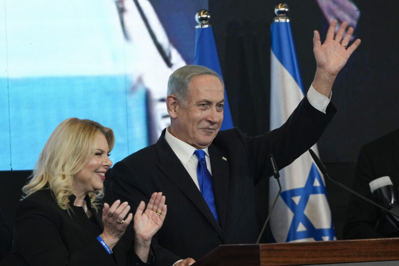 Benjamin Netanyahu, former Israeli Prime Minister and the head of Likud party, accompanied by his wife Sara waves to his supporters after first exit poll results for the Israeli Parliamentary election at his party's headquarters in Jerusalem, Wednesday, Nov. 2, 2022. (AP Photo/Tsafrir Abayov)