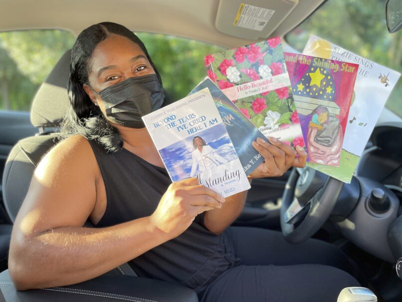 In this Wednesday, Aug. 10, 2022, photo in Princeton, N.J., Tomika Reid holds books that she’s authored. Reid, a single mother and children’s book author in the Princeton area, works as a ride-hailing service driver and tries to inspire passengers through spiritual guidance on the road as part of what she sees as a ride-hailing ministry. (AP Photo/Luis Andres Henao)