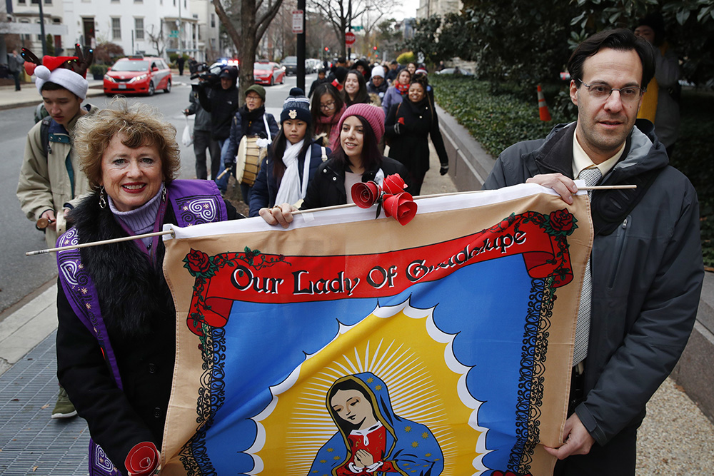 FILE - Rev. Sharon Stanley-Rea, left, and Eli McCarthy, right, hold a banner of Our Lady of Guadalupe during a march with others through Capitol Hill in support of the Deferred Action for Childhood Arrivals (DACA) program, Tuesday, April 12. December 2017, Washington.  (AP Photo/Jacquelyn Martin)