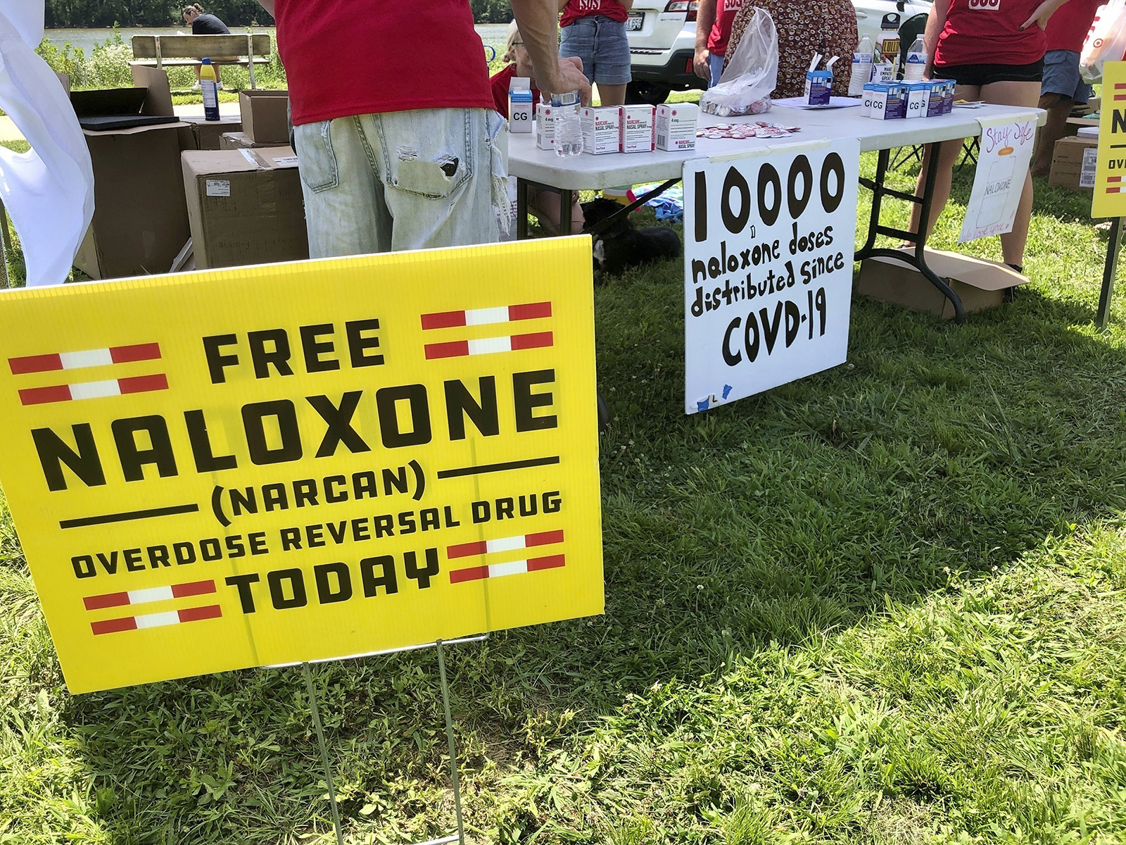 FILE - Signs are displayed at a tent during a health event on June 26, 2021, in Charleston, W.Va. Volunteers at the tent passed free doses of naloxone, a drug that reverses the effects of an opioid overdose by helping the person breathe again. (AP Photo/John Raby, File)