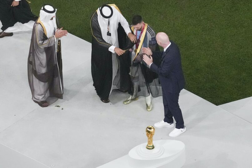Argentina's Lionel Messi is honored with a cloak prior to receiving the World Cup trophy at Lusail Stadium in Lusail, Qatar, on Dec. 18, 2022.  (AP Photo/Thanassis Stavrakis)