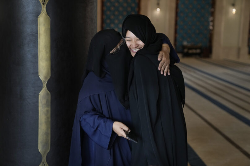 Guide Riffat Ishfaq, left from Pakistan embraces tourist Fatima Gracia from El Salvador, in Doha, Qatar, Tuesday, Dec. 6, 2022. In Qatar to enjoy the World Cup with friends, Gracia, the Salvadoran visitor took a day off from soccer to go sightseeing at the Katara mosque, where preachers have been introducing Islam in multiple languages to curious fans from around the world. (AP Photo/Jorge Saenz)
