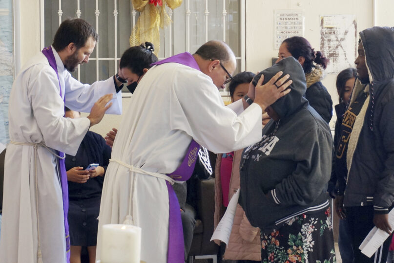 The Rev. Brian Strassburger, left, and the Rev. Flavio Bravo, right, bless migrants during Mass at the Casa del Migrant shelter in Reynosa, Mexico, on Dec. 15, 2022. Hope and tension have both been rising at Casa del Migrant and the few other shelters in this border city where thousands of migrants await news of U.S. border policy changes possibly less than a week away. (AP Photo/Giovanna Dell'Orto)