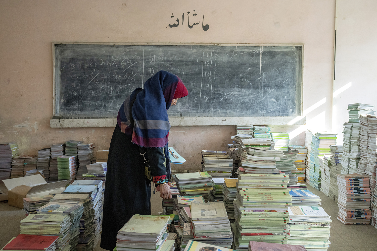 Amanah Nashenas, an Afghan teacher, collects books in a school in Kabul, Afghanistan, Dec. 22, 2022. The country’s Taliban rulers earlier in the week ordered women nationwide to stop attending private and public universities effective immediately and until further notice. They also banned girls from middle school and high school, barred women from most fields of employment and ordered them to wear head-to-toe clothing in public. Women are also banned from parks and gyms. (AP Photo/Ebrahim Noroozi)