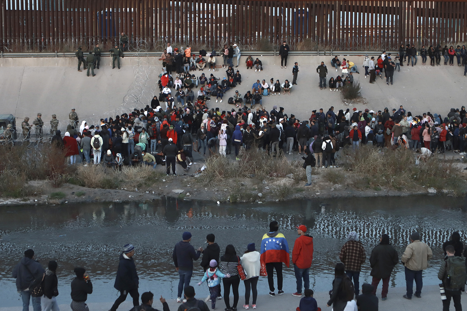 Migrants gather at a crossing into El Paso, Texas, as seen from Ciudad Juarez, Mexico, Dec. 20, 2022. Tensions remained high at the U.S-Mexico border Tuesday amid uncertainty over the future of restrictions on asylum-seekers, with the Biden administration asking the Supreme Court not to lift the limits before Christmas. (AP Photo/Christian Chavez)