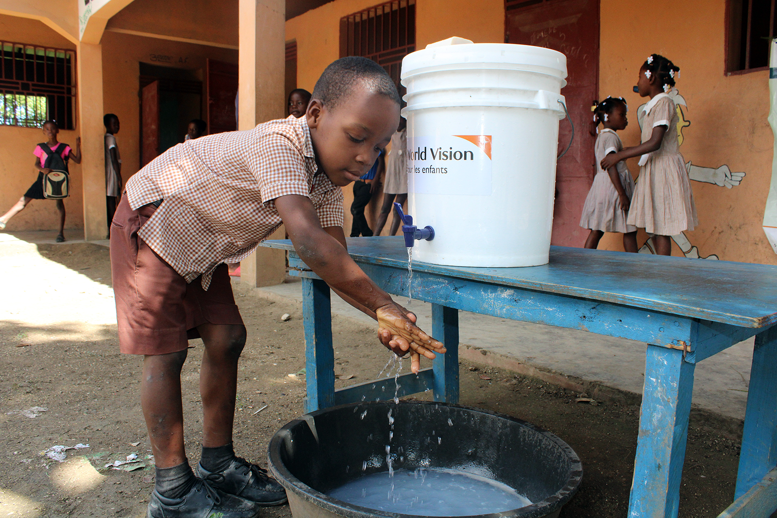A young student washes his hands at a water station provided by World Vision in Haiti. Photo courtesy of World Vision