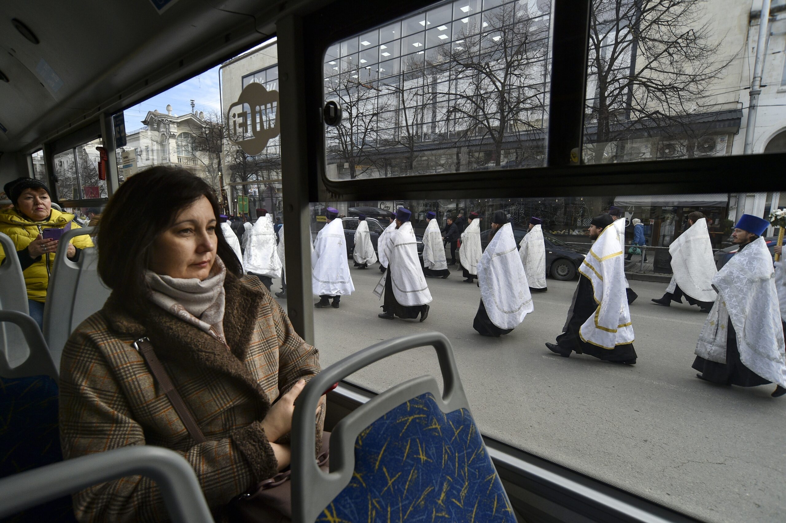 A woman looks through a bus window as Russian Orthodox priests and believers participate in the procession celebrating Orthodox Christmas in Sevastopol, Crimea, Saturday, Jan. 7, 2023. Orthodox Christians celebrate Christmas on Jan. 7, in accordance with the Julian calendar. (AP Photo)