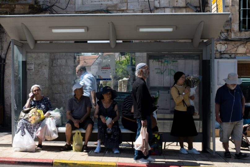 People wait at a bus stop at the Mahane Yehuda market in Jerusalem. (Alexi Rosenfeld/Getty Images)