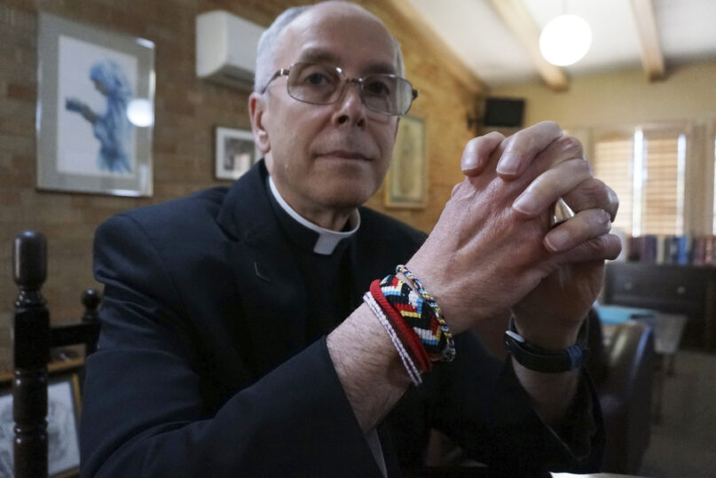 Bishop Mark Seitz of El Paso sits for a portrait in his office in El Paso, Texas, on Monday, April 4, 2022. The friendship bracelets on his wrist were braided by girls housed at a shelter on nearby Fort Bliss Army base for unaccompanied minors who crossed the U.S.-Mexican border. “Immigrants have had the experience of leaving everything that helped them to feel at home and secure in this life behind, and to depend utterly on God as they journey. ... They have so much to teach us about how God will accompany us on our journey,” Seitz says. (AP Photo/Giovanna Dell'Orto)