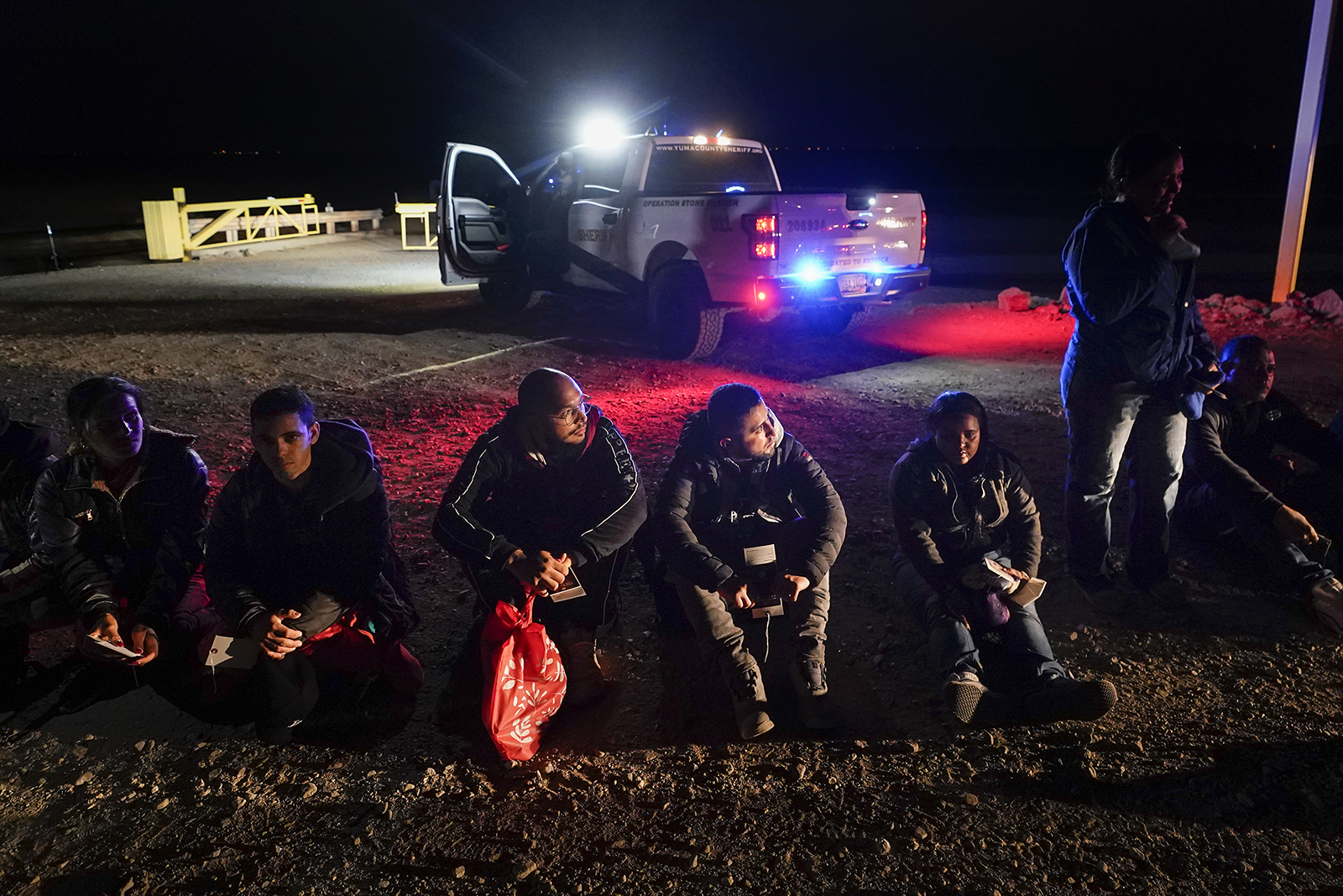 Migrants wait to be processed after crossing the border Friday, Jan. 6, 2023, near Yuma, Arizona. (AP Photo/Gregory Bull)