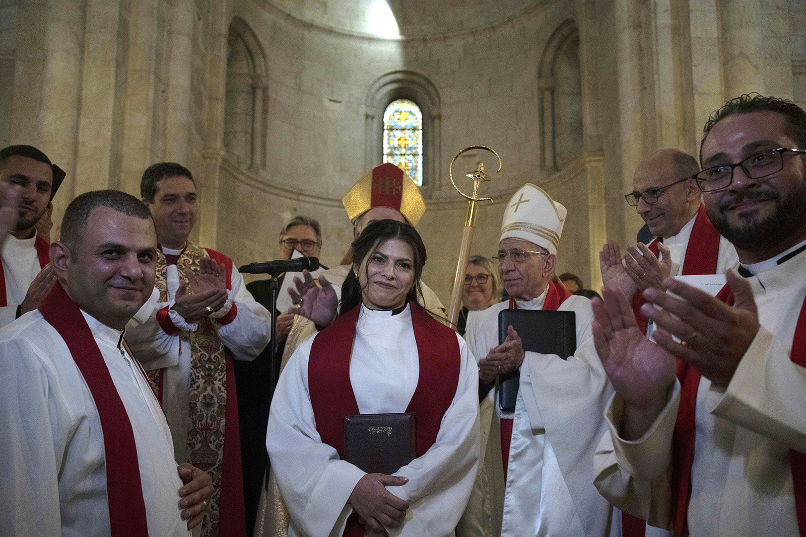 The Rev. Sally Ibrahim Azar, center, a Palestinian Christian and council member of the Lutheran World Federation, is applauded by clergy after she was ordained as the first female pastor in the Holy Land, in the Old City of Jerusalem, Jan. 22, 2023. (AP Photo/Maya Alleruzzo)