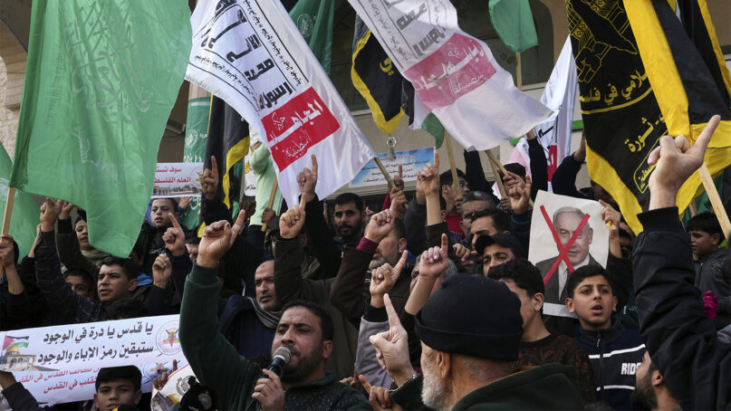 Hamas and Islamic Jihad supporters raise their hands while chanting slogans, as some hold crossed-out pictures of Israeli Prime Minister Benjamin Netanyahu, during a protest in support of Al-Aqsa Mosque compound and against Itamar Ben-Gvir's recent visit to the site, after Friday prayer in front of Al-Hoda Mosque in Rafah refugee camp, southern Gaza Strip, Friday, Jan. 6, 2023. (AP Photo/Adel Hana)