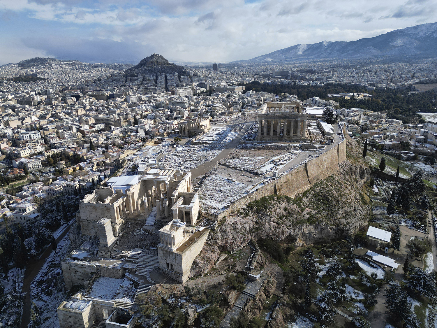 Parts of the Acropolis are covered in snow as the Parthenon temple stands atop of the ancient hill, after a snowfall, in Athens, Greece, Monday, Feb. 6, 2023. High winds and a cold snap in Greece halted ferry services and highway traffic and dusted the Acropolis and other ancient monuments in Athens with snow Monday. (AP Photo/Thanassis Stavrakis)